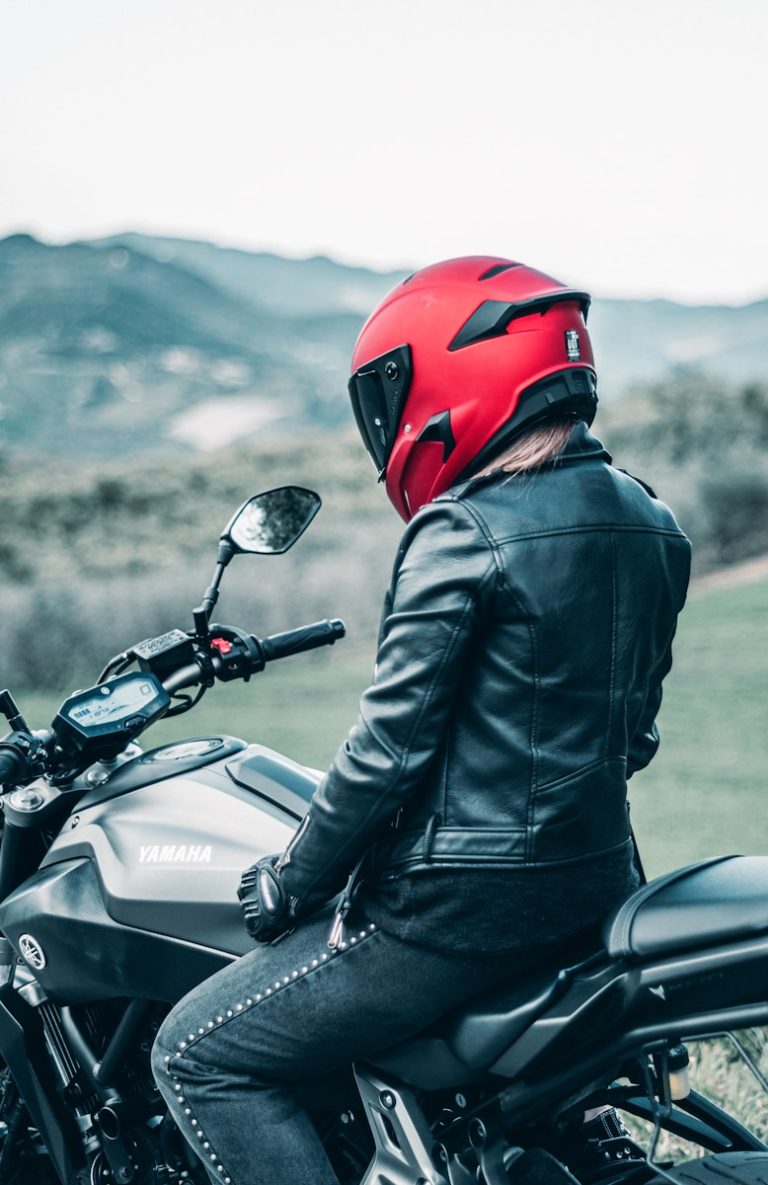 man in black leather jacket wearing red helmet riding black honda motorcycle